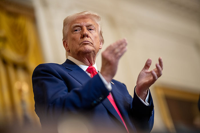 Donald Trump clapping during an event, representing the news about Trump firing Kamala Harris’ husband Doug Emhoff.