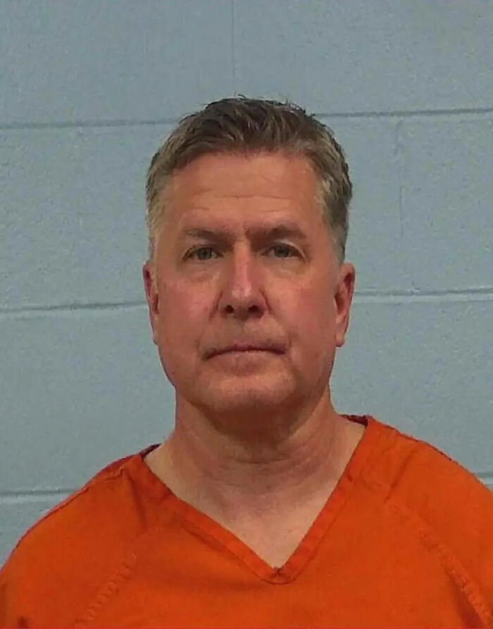 Mugshot of a man in an orange prison uniform linked to a divorce lawyer charged in a client's cold-case murder.