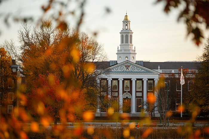 Harvard University building in autumn with colorful trees, representing Trump's hunt targeting international students.