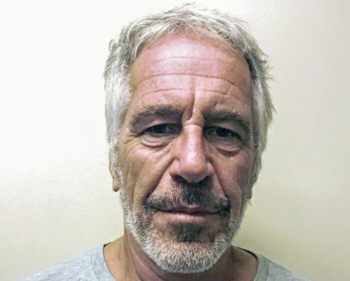 Mugshot of Jeffrey Epstein with gray hair and beard, relevant to experts questioning orange figure near jail cell.