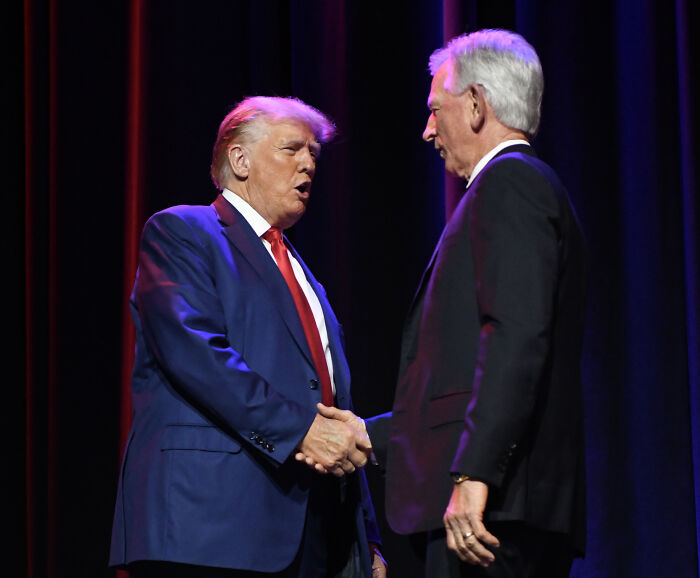 Donald Trump and GOP senator shaking hands on stage during a political event discussing Trump’s cankles claim.