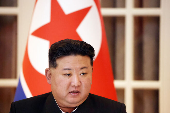 Kim Jong Un’s sister in formal attire with North Korean flag in background rejecting South Korea dialogue efforts.