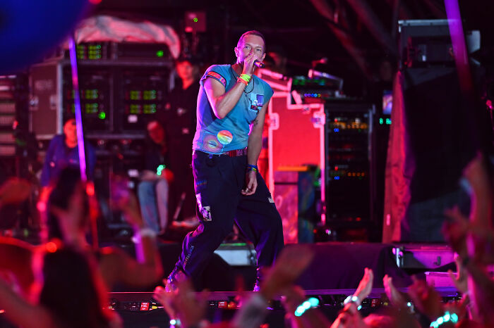 Lead singer of Coldplay performing on stage with dynamic lighting, highlighting the discussion on privacy in public settings.