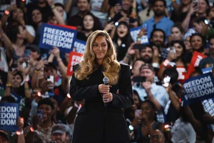 Beyoncé holding microphone at rally with crowd, related to Donald Trump blasting and prosecution over Kamala Harris support.