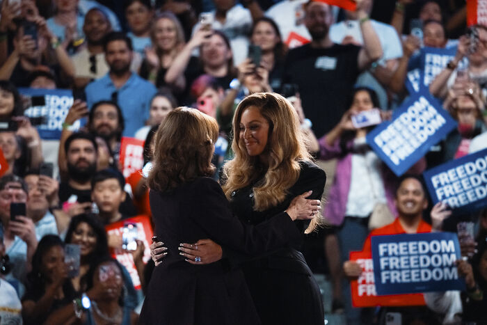 Beyoncé embracing a woman at an event with crowd holding freedom signs, related to Donald Trump and Kamala Harris support controversy.