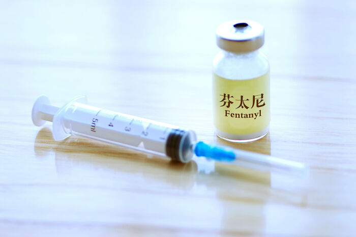 Vial labeled fentanyl alongside a syringe on a wooden surface, highlighting fentanyl overdose crisis concerns.