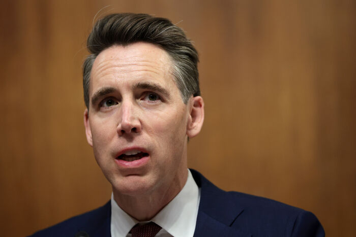 Josh Hawley speaking at a hearing, wearing a suit and tie, discussing Medicaid cuts and legislative actions.