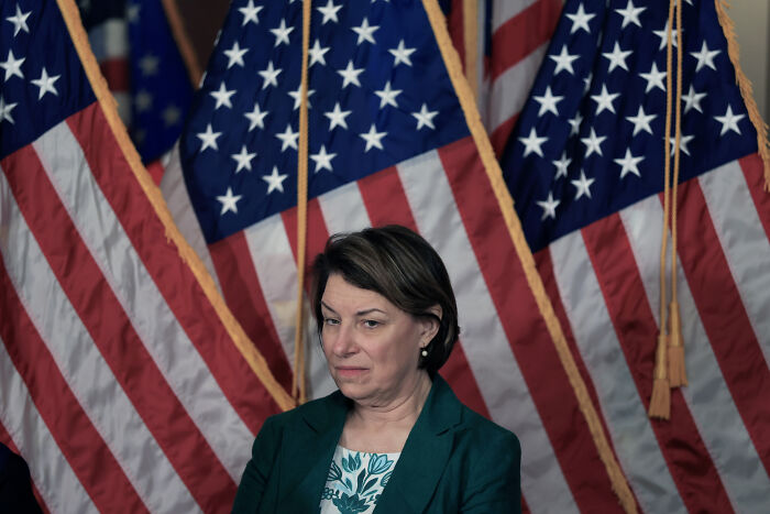 Senator Murkowski standing before multiple American flags, reacting to swing-vote decision on GOP bill amid criticism. Senator Murkowski standing before multiple American flags, reacting to swing-vote decision on GOP bill amid criticism.