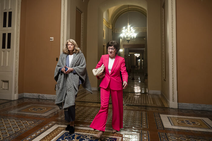 Two women walking in a hallway with intricate tile flooring discussing the swing-vote Murkowski on GOP bill decision. Two women walking in a hallway with intricate tile flooring discussing the swing-vote Murkowski on GOP bill decision.