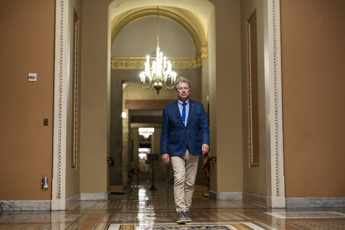 Man walking in a hallway under chandelier representing swing-vote Murkowski casting decisive yes on GOP bill. Man walking in a hallway under chandelier representing swing-vote Murkowski casting decisive yes on GOP bill.