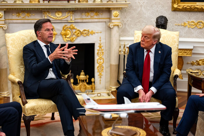 Donald Trump and another man in a formal meeting discussing Ukraine arms and Trump’s stance on Putin’s involvement.