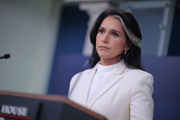 Woman in white blazer speaking at a podium about Senate appointing January 6 conspiracy theorist Joe Kent to lead counterterrorism.
