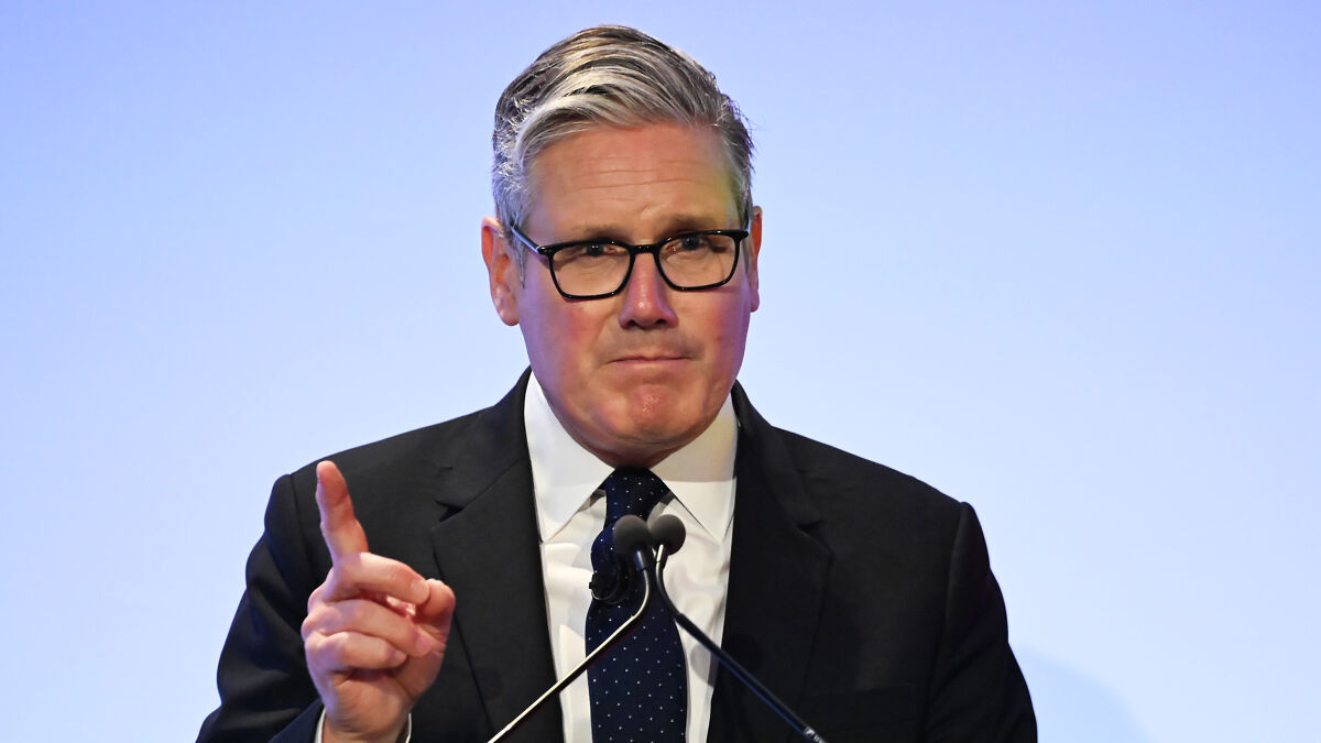 U.K. PM Starmer wearing glasses and a suit, speaking at a podium about banning trans people from single-sex spaces.