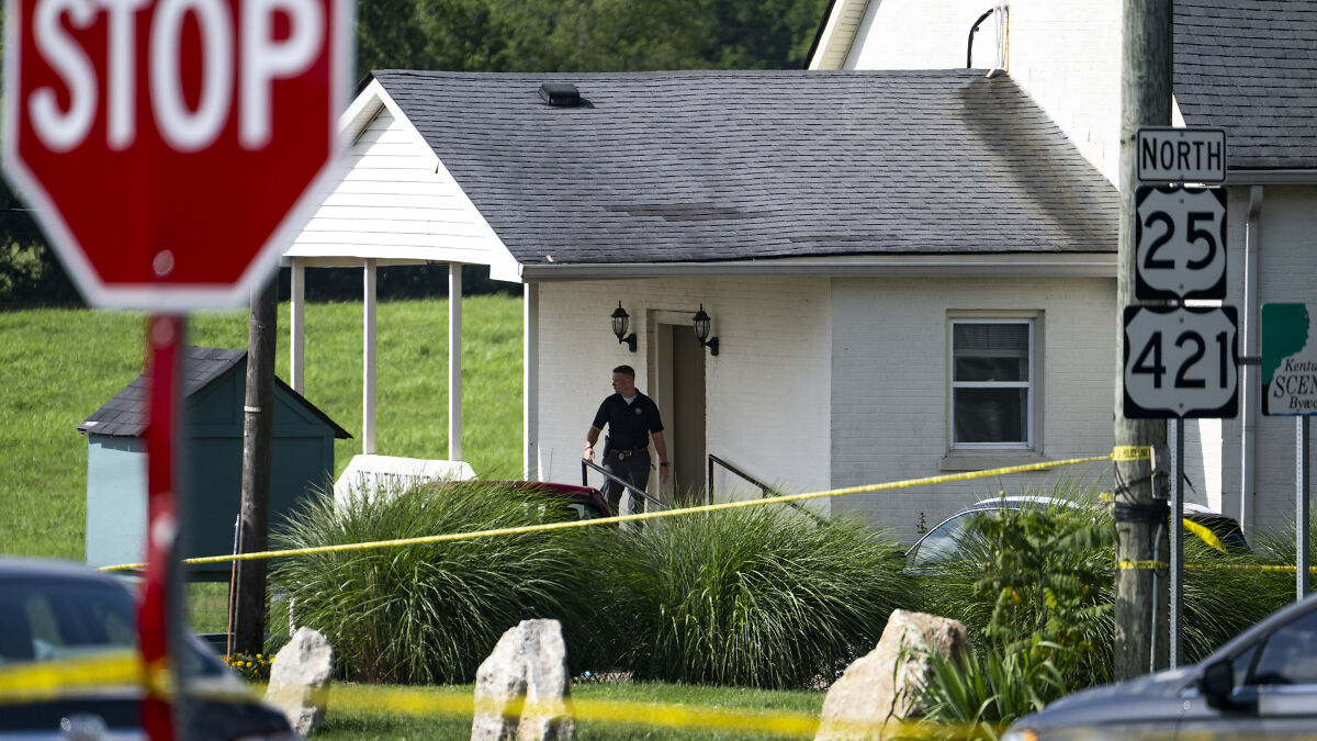 Police and crime scene tape outside a white building near highways 25 and 421 after shootings near Kentucky airport and church