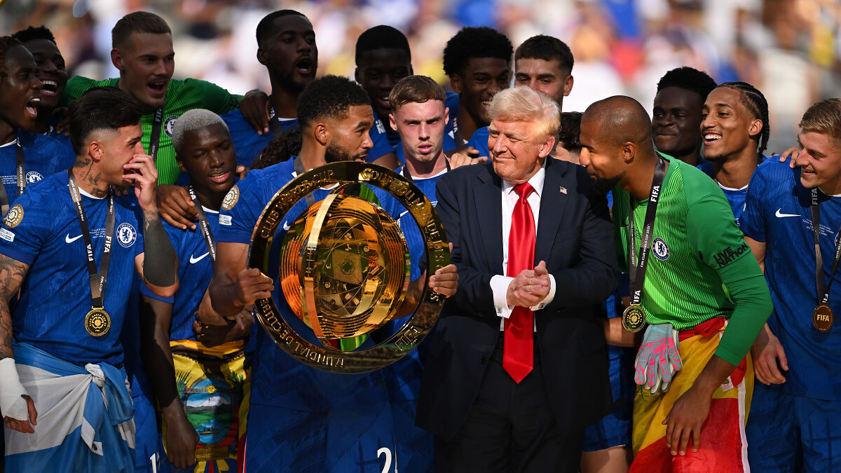 Chelsea players holding Club World Cup trophy with Donald Trump during trophy presentation amid crowd boos.