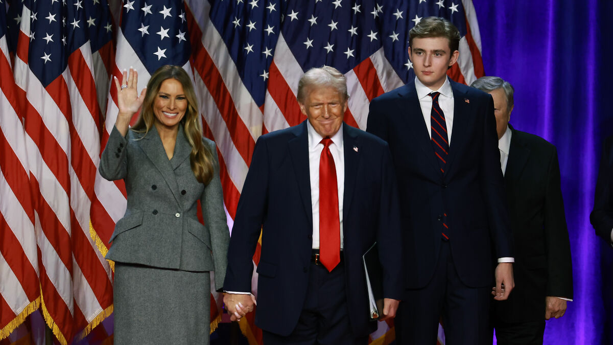 Barron Trump standing with family in front of U.S. flags, representing Barron Trumpu2019s U.S. citizenship discussion.