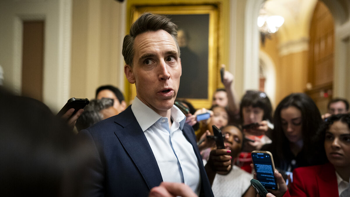 Josh Hawley speaking to reporters in a crowded hallway, discussing Medicaid cuts and legislative efforts.