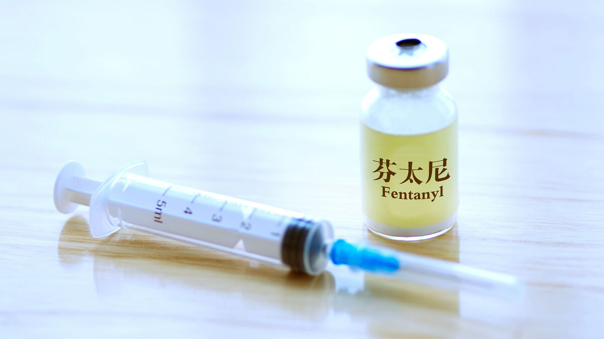 Syringe and vial labeled fentanyl on a wooden surface highlighting the fentanyl overdose crisis issue.
