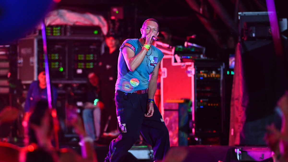 Coldplay lead singer performing on stage with colorful lights, highlighting the question of privacy in public events.