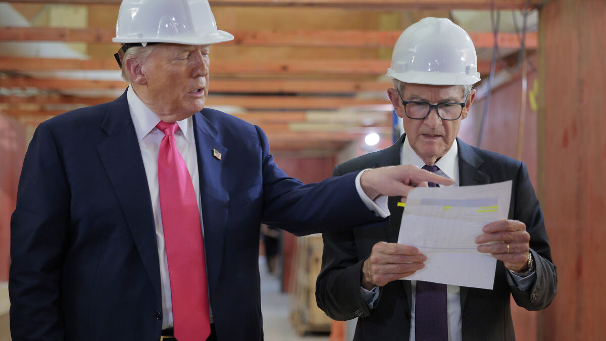 Federal Reserve Chair Jerome Powell in a hard hat reviewing documents with Donald Trump during a construction site visit