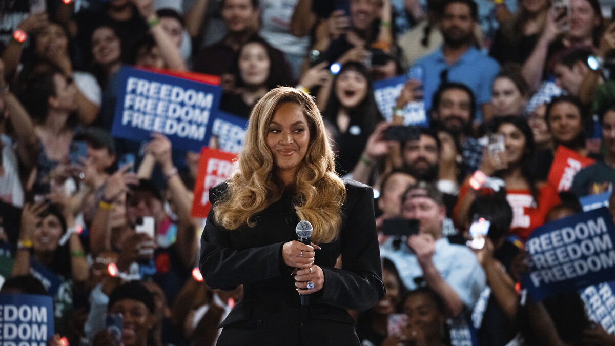 Beyoncu00e9 holding a microphone at a crowded event as Donald Trump blasts her and calls for prosecution over Kamala Harris support.
