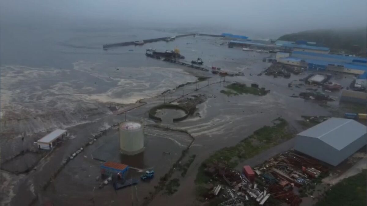 Flooded industrial area with tsunami waves striking Hawaii after a powerful earthquake near Russia triggers evacuations.