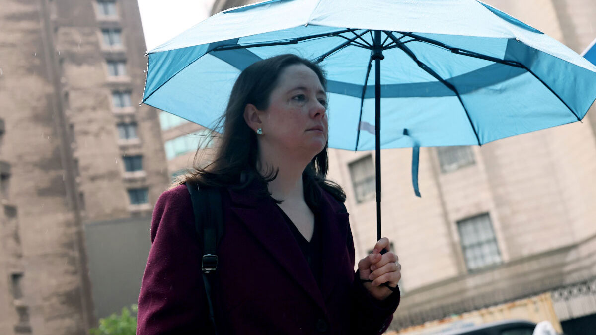 James Comeyu2019s daughter holding a blue umbrella outside a government building after DOJ high-profile prosecutions.