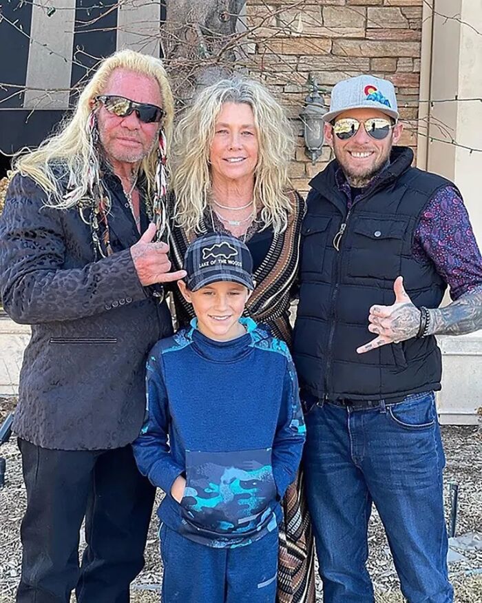 Dog The Bounty Hunter’s family posing outside a home, featuring his step-grandson and father in casual attire.