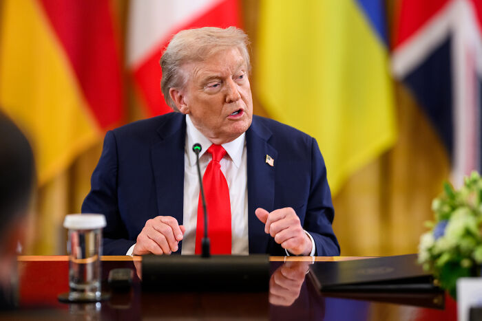 Donald Trump speaking at a conference table, focusing on intelligence subversion and clearance revocations.