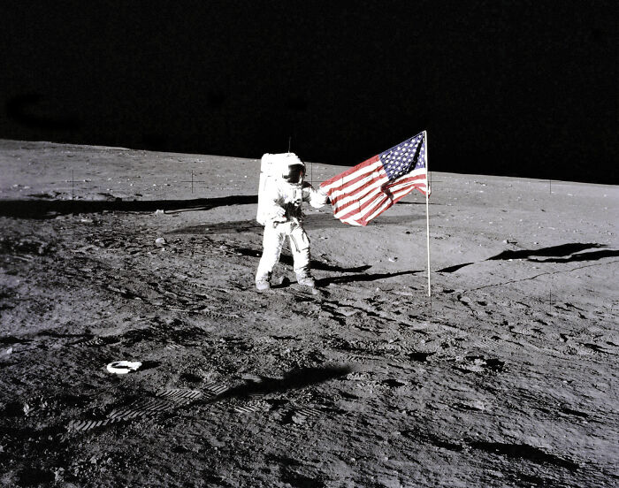 Astronaut on the moon next to the American flag, symbolizing NASA’s plans for a fast-tracked nuclear reactor mission.