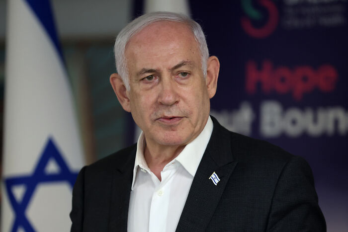 Israeli official speaking at event with flag in background, related to major countries recognizing Palestine.