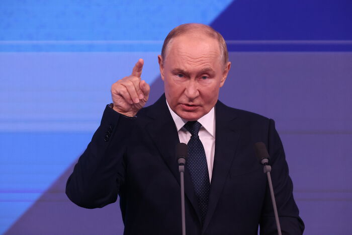 A man in a dark suit gesturing while speaking at a podium, highlighting lessons to avoid World War III.