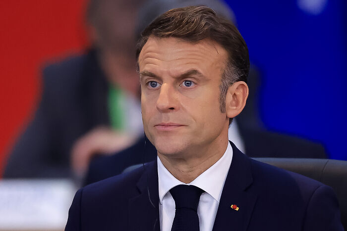 Man in a dark suit and tie sitting attentively during a political event discussing major countries recognizing Palestine.