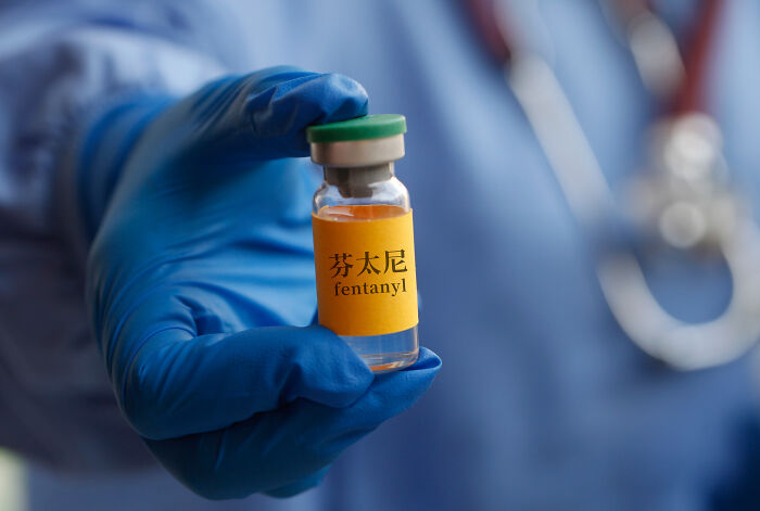 Gloved hand holding a vial labeled fentanyl, highlighting concerns amid Canada disappointed by Trump tariff hikes on allies.