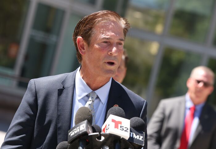 Erik Menendez speaking at a press conference with multiple microphones, related to denied parole after slaying parents.