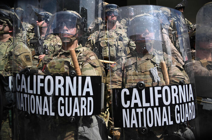 California National Guard troops in riot gear holding shields, prepared for deployment in Washington, D.C. crime crackdown efforts.