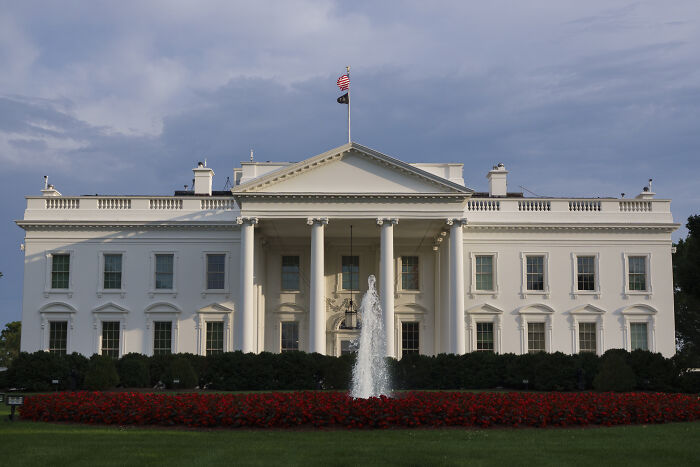 The White House with a fountain and flag, related to experts warning on Trump’s anti-woke AI and complex LLMs.