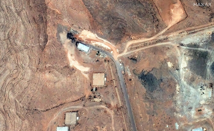 Aerial satellite image showing arid terrain and roads, highlighting the 80-year aftermath of Hiroshima and Nagasaki impact.