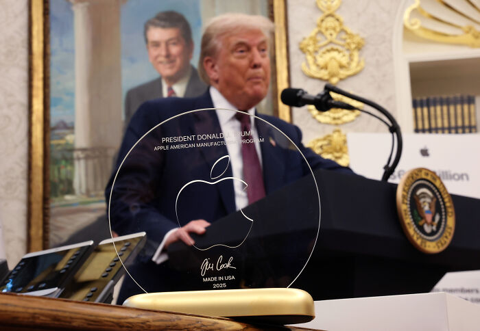 Apple’s Tim Cook presenting a gold Apple award to Donald Trump at the White House during a manufacturing event.
