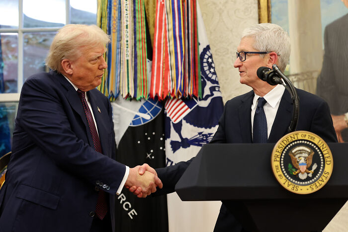 Apple’s Tim Cook and Donald Trump shaking hands at the White House during a meeting with US presidential seal visible