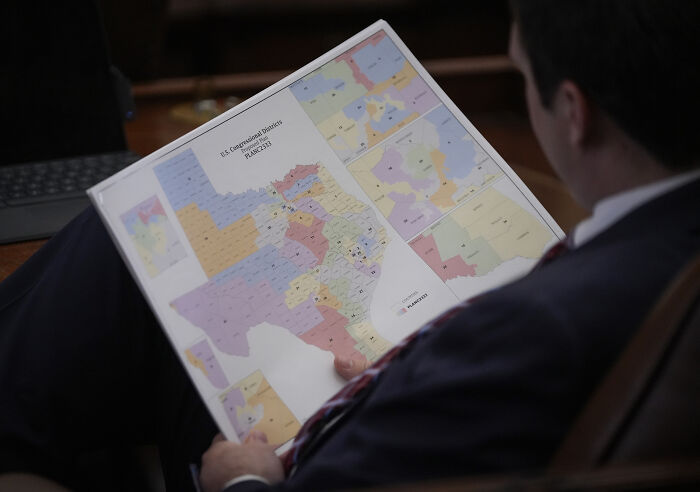 Man reviewing a detailed California redistricting map during a legislative session on redistricting plans. Man reviewing a detailed California redistricting map during a legislative session on redistricting plans.