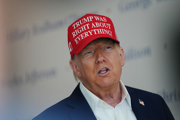 Donald Trump wearing a red hat stating Trump was right about everything during a public appearance.
