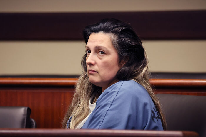 A woman in a blue prison uniform sitting in a courtroom, related to Emmanuel Haro’s dad confession case.