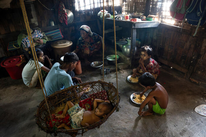 Family inside a wooden home in Myanmar, highlighting the impact of junta’s sham election amid atrocity allegations.
