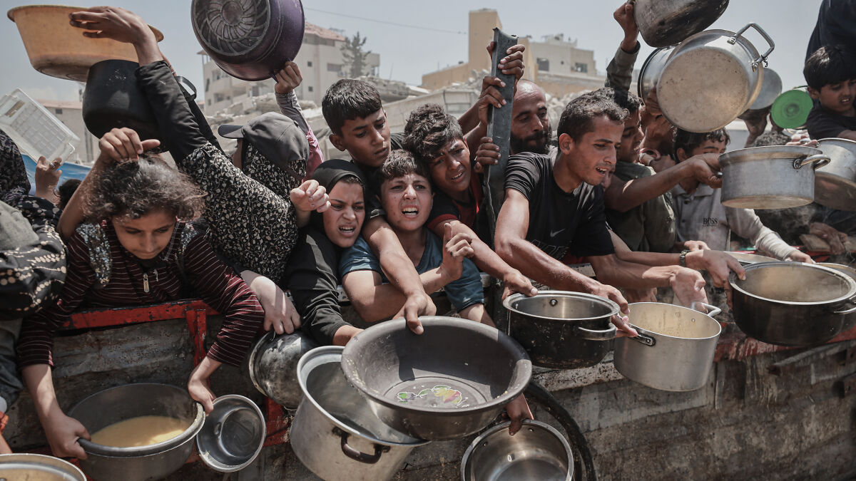 People in Palestine crowd with pots and containers seeking food aid amid recognition by major countries.