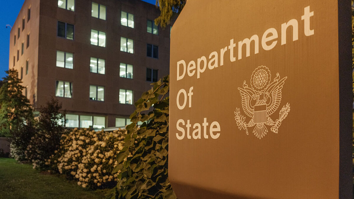 U.S. Department of State building with illuminated windows at dusk, related to foreign tourists visa fees pilot program.
