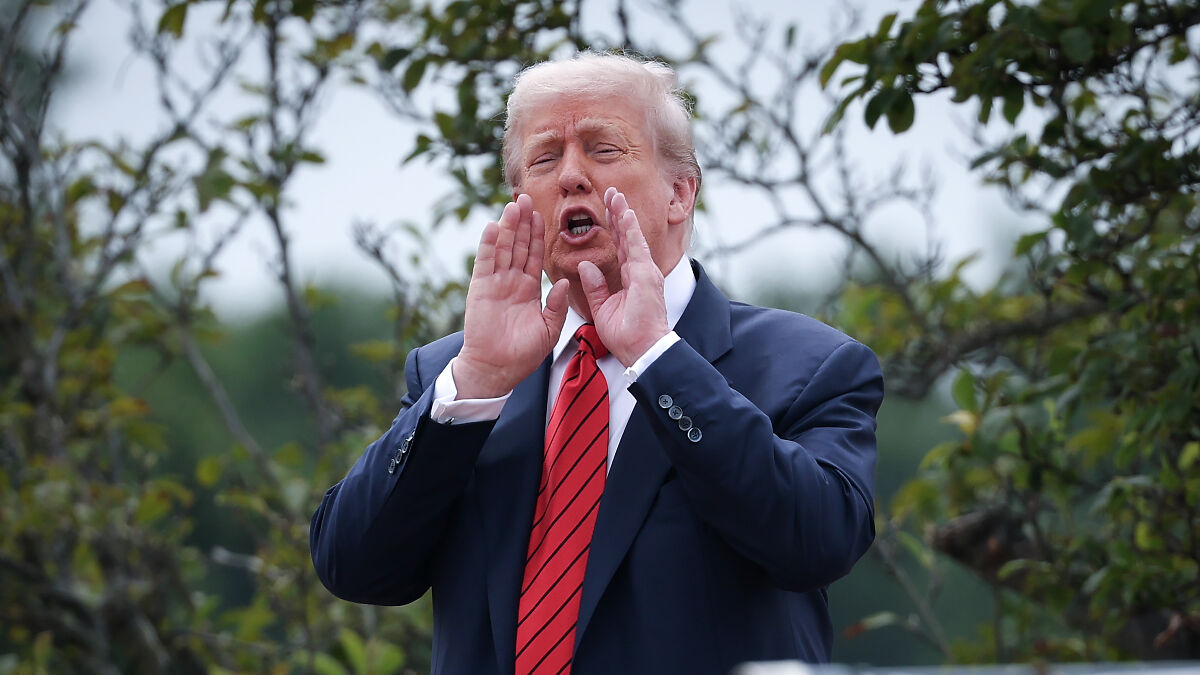 Donald Trump hollering outdoors with hands cupped near mouth, surrounded by greenery, capturing White House rooftop moment.