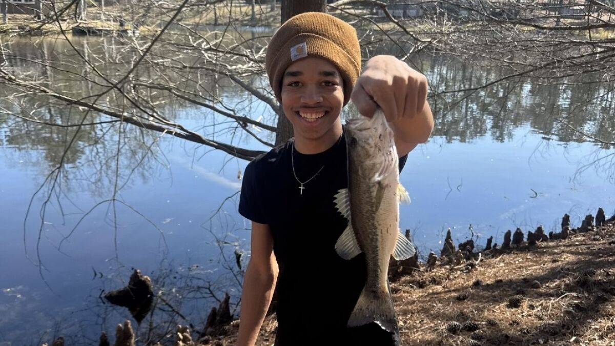 Young man smiling by a lake holding a fish, relating to Giovanni Pelletier family finding his body after last text message.