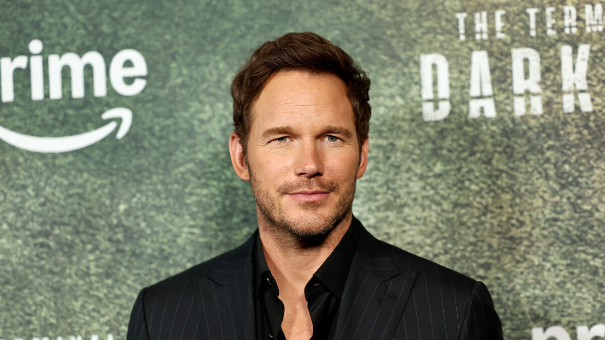 Chris Pratt smiling at event, lauding his wifeu2019s relative RFK Jr. amid MAHA controversy in a black suit.