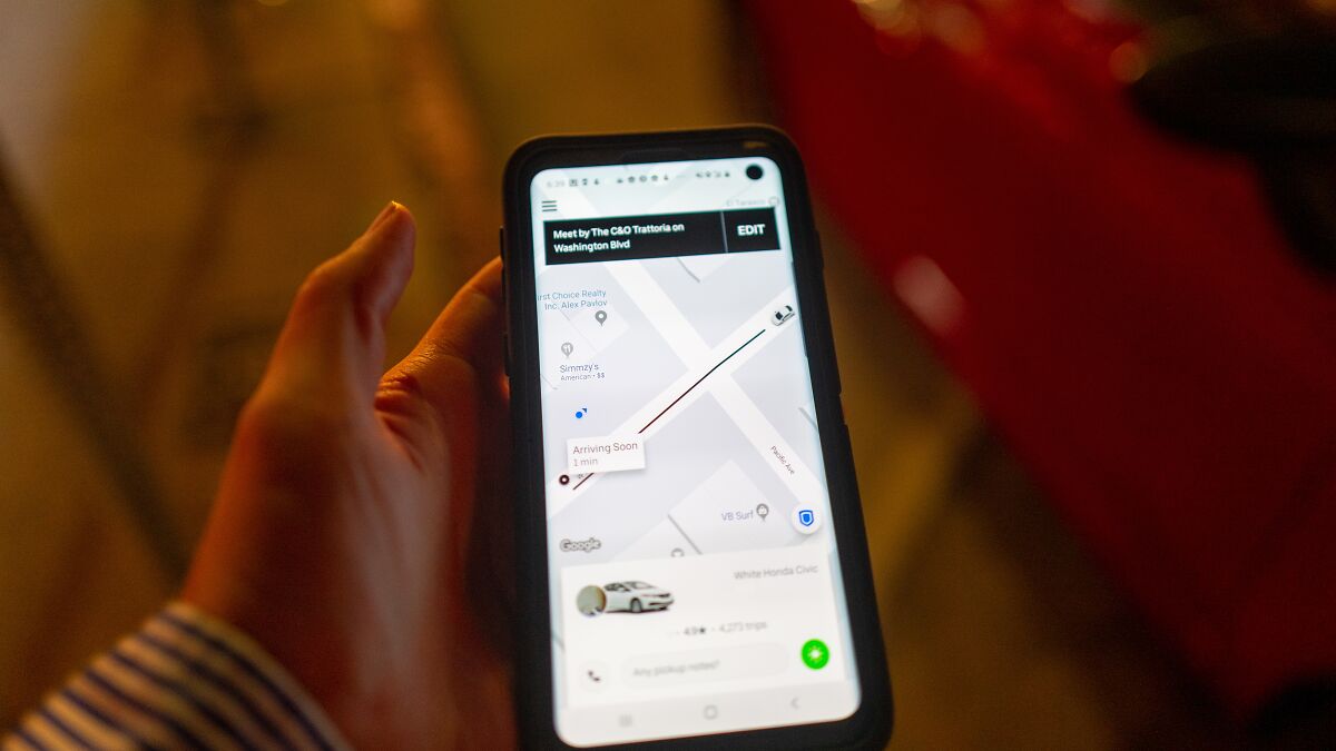 Hand holding smartphone showing ride app map highlighting Uber driver screening failures and legal issues in U.S.